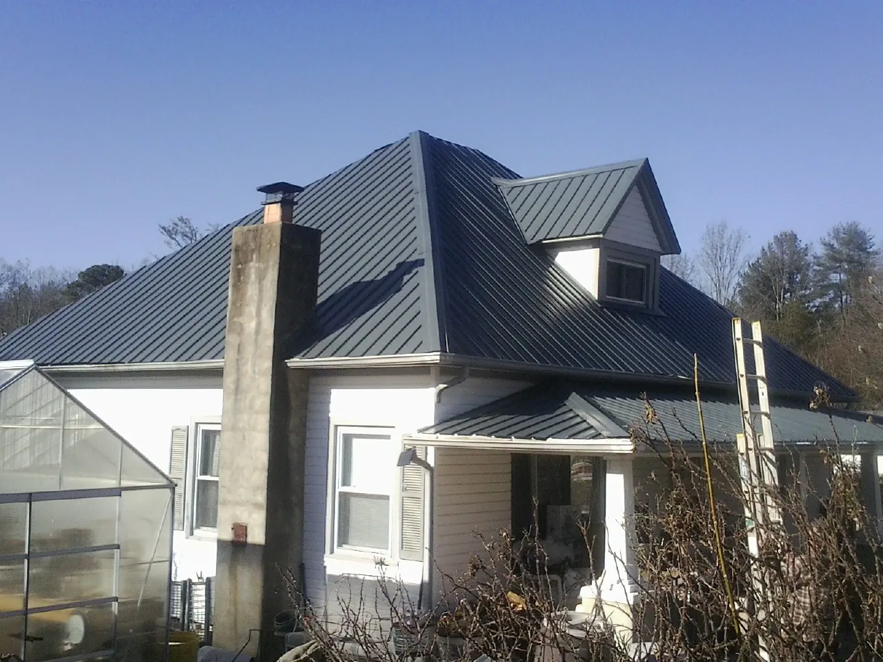 Dark blue standing seam metal roof on a white farmhouse with dormer — Slate & Tile Roof Repair by Roofing Brothers in Tygh Valley