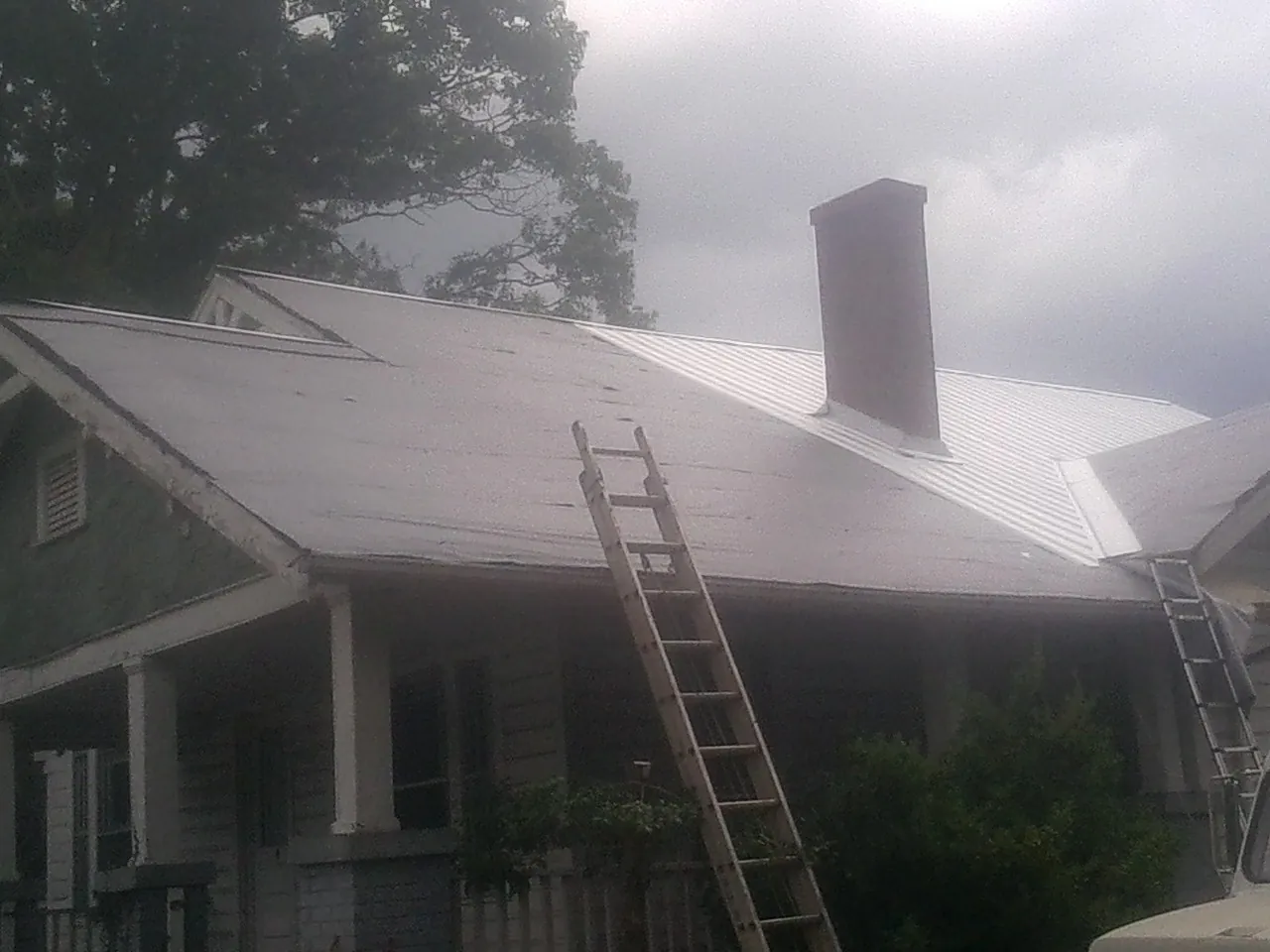 Ladders against a metal roof on an older home with a brick chimney in Tygh Valley