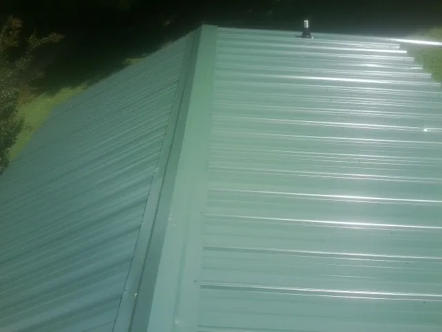 New green metal panels meeting at the ridge of a roof — Flat Roof Repair work by our crew in Tygh Valley
