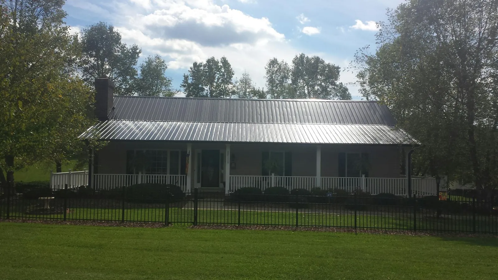 Gray metal roof on a brick ranch with a full width front porch — Gutter Guard Installation work by our crew in Tygh Valley