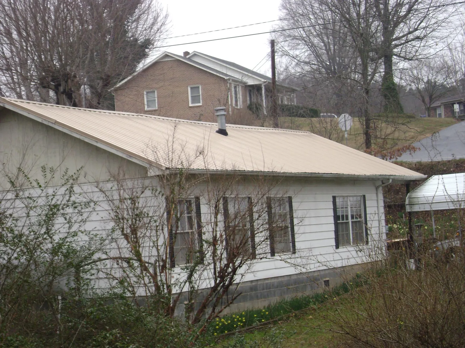 Tan metal roof on a white sided house set into a hillside — Commercial Roofing by Roofing Brothers in Tygh Valley