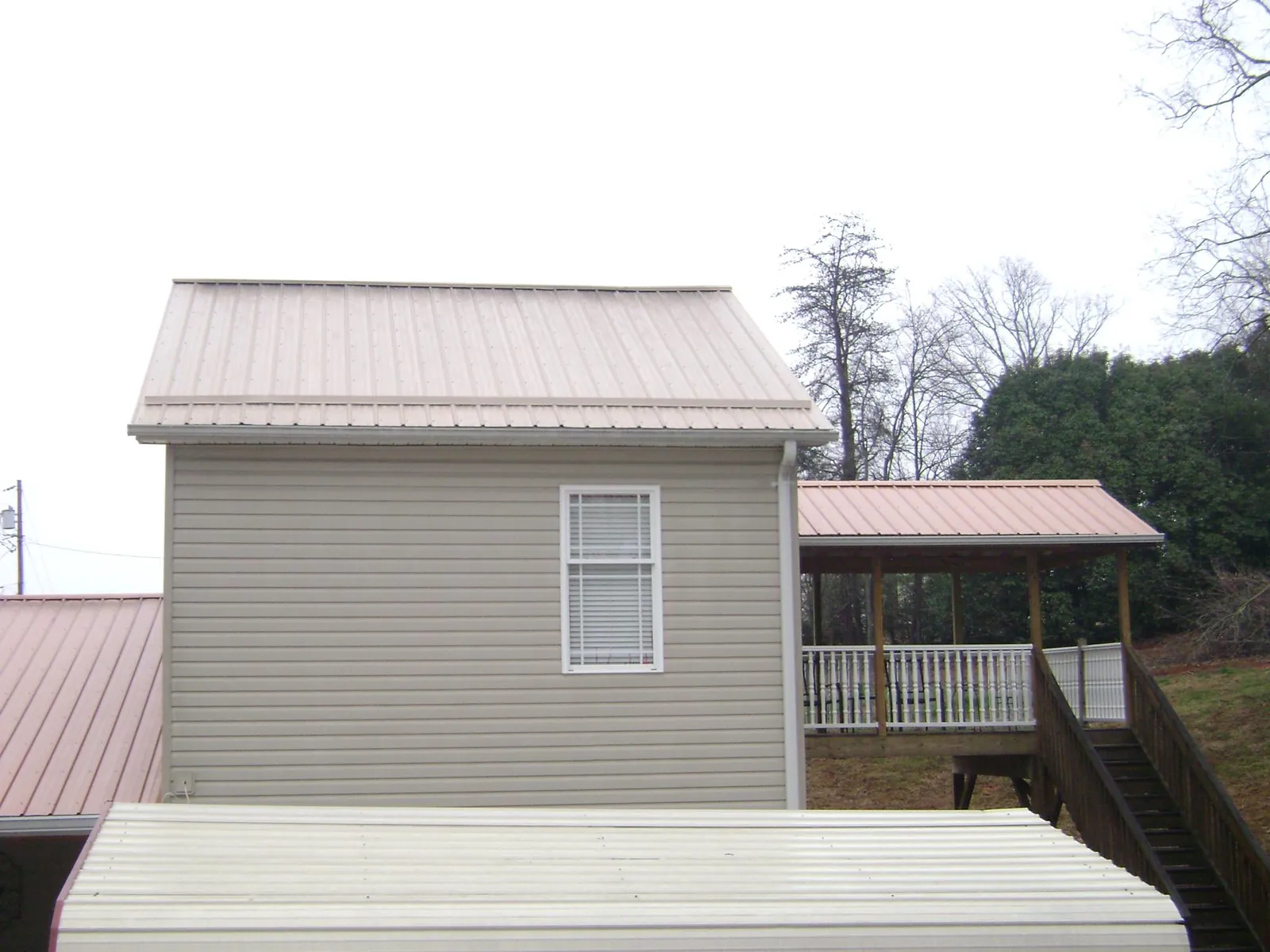 Tan metal roofs on a two story addition and attached porch, from a Roof Replacement job in Tygh Valley