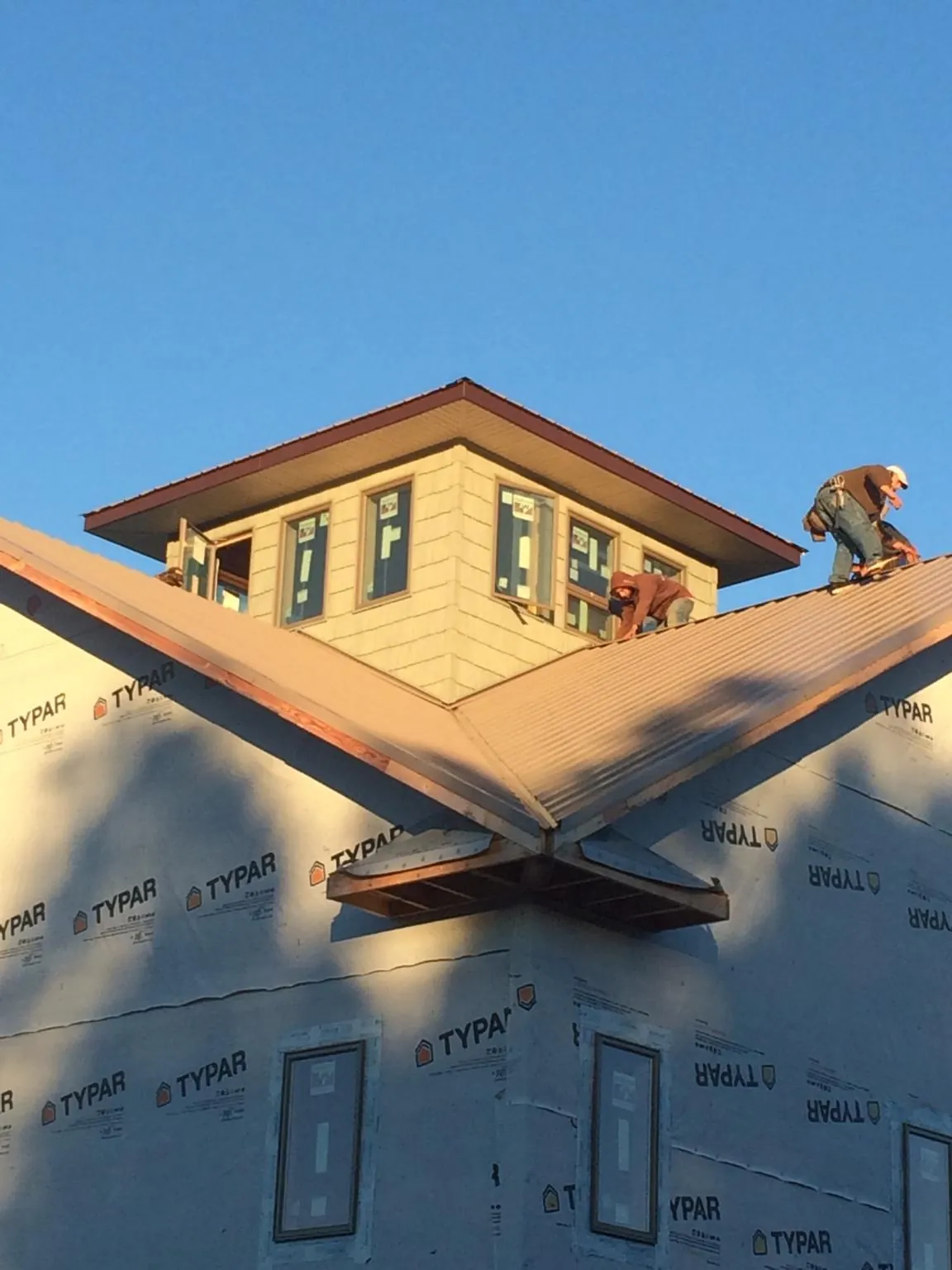 Roofers working around a rooftop cupola on a new metal roof at sunset — Roof Waterproofing in Tygh Valley by Roofing Brothers